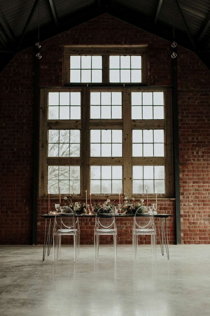 Clear chairs, pink and red candles and earthy foliage wedding table decorations at The Giraffe Shed