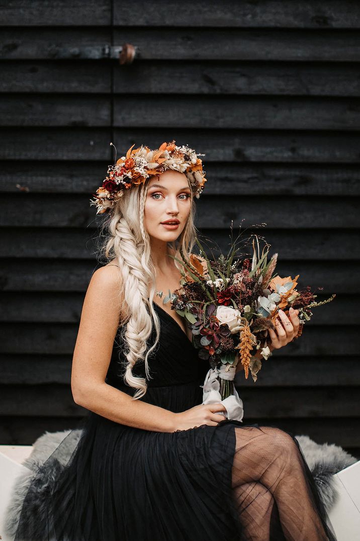 Halloween wedding with the bride in a black wedding dress with a autumnal flower crown with bunny grass and autumnal leaves with bouquet