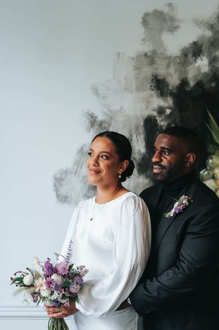 Bride in satin balloon sleeve wedding dress with the groom in an all black suit 