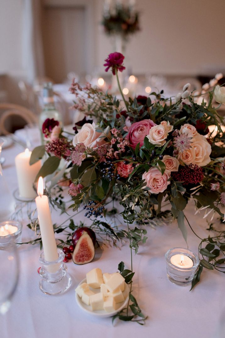 Romantic blush pink and peach floral centrepiece with candle light and figs