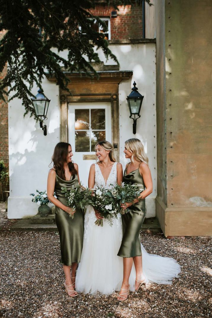 Bridesmaids in sage green satin bridesmaid dresses with bride in lace v-neck wedding dress 