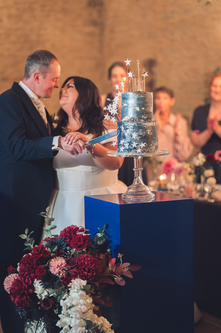 The bride and groom cut their night sky inspired moon and stars wedding cake 