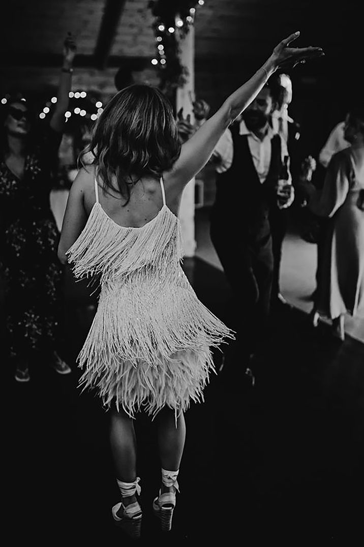 Bride dancing at her wedding reception wearing a stylish mini tassel dress by Carrie Lavers Photography