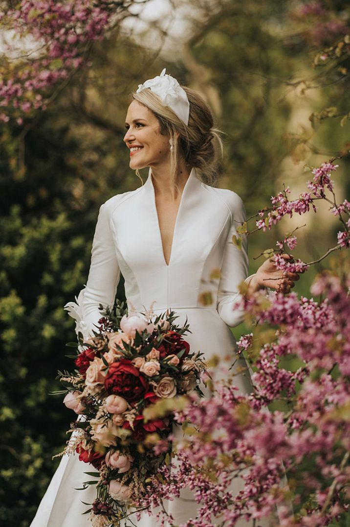 Bride in classic long sleeve wedding dress with red and pink flower wedding bouquet