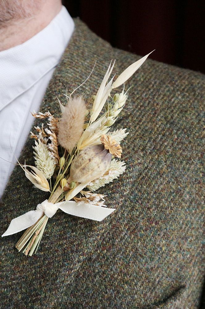 Pale dried flower buttonhole on tweed lapel