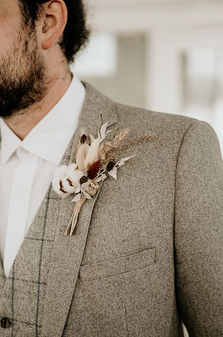 Groom in a beige wool suit at a boho wedding with a neutral dried flower buttonhole 