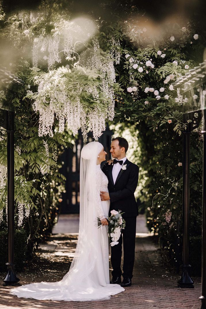 Bride and groom portrait at under white and green wedding vines 