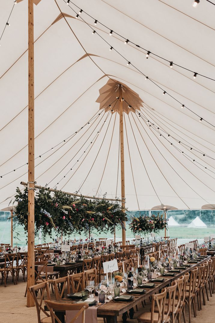 Sperry tent wedding reception with flower installation and festoon lights decor 