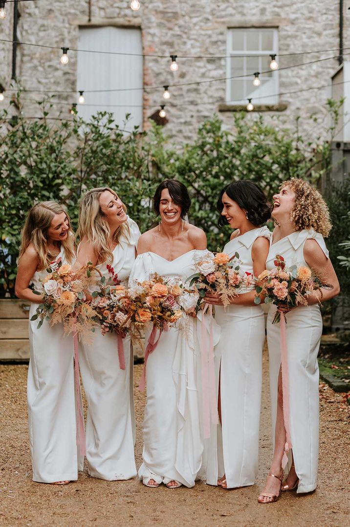 Bridal party wearing one shoulder long white bridesmaid dresses