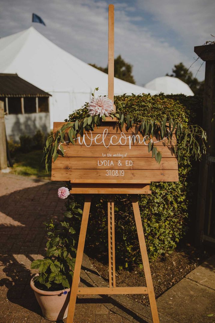 DIY wooden wedding welcome sign with fauna decorations and large pink flowers