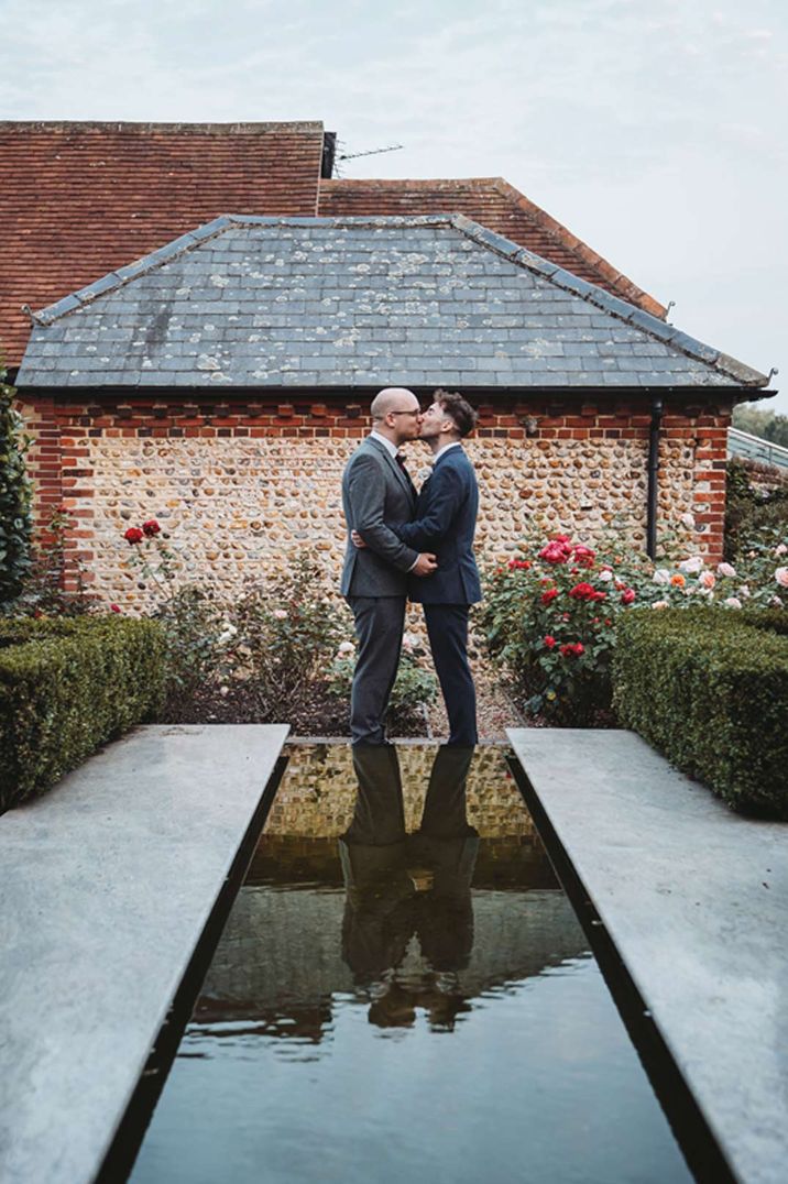 Two grooms embracing at Southend Barns, one of the best UK barn wedding venues 