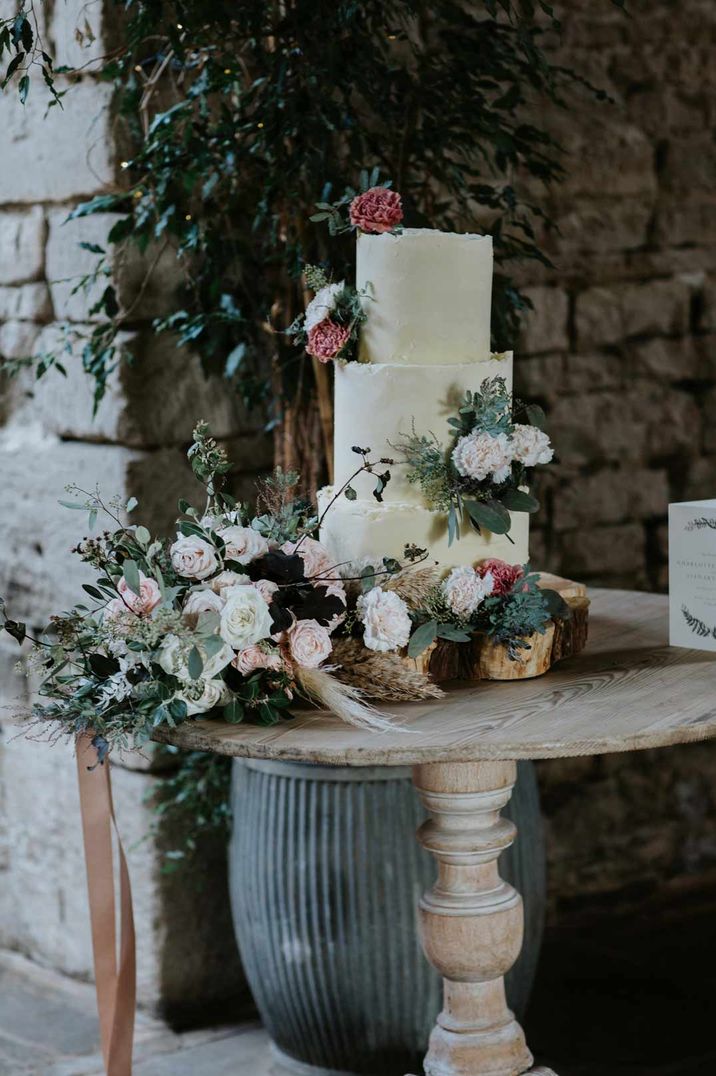 Three tier plain buttercream wedding cake with pink carnations with pink and white rose bouquet decorations