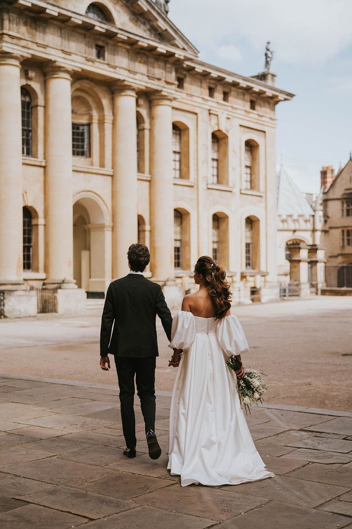 The bride and groom walk around and explore the city together on their wedding day 