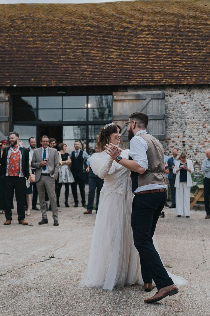 Newlyweds stand outdoors for first dance on their wedding day in rustic farm setting