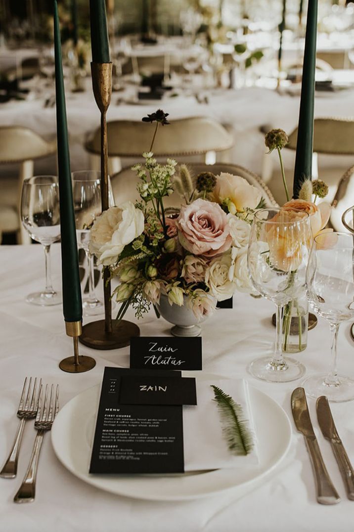 Elegant place setting with green taper candles, floral centrepiece and menu card