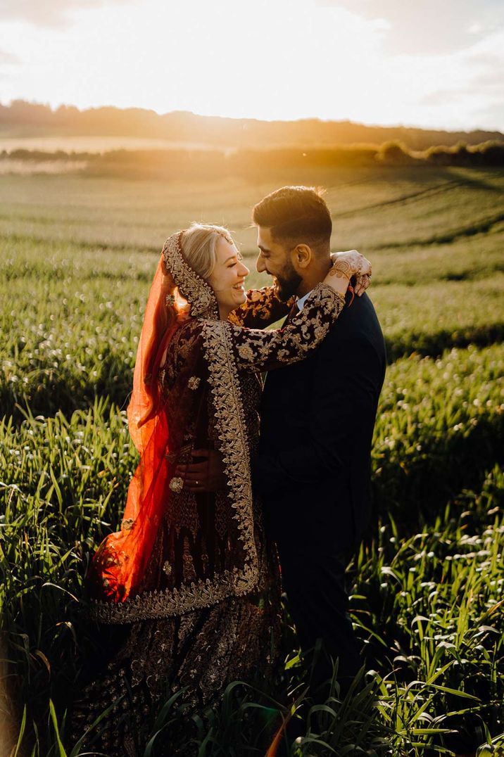 Newlyweds embracing on the grounds of The Barn At Upcote, one of the best UK barn wedding venues