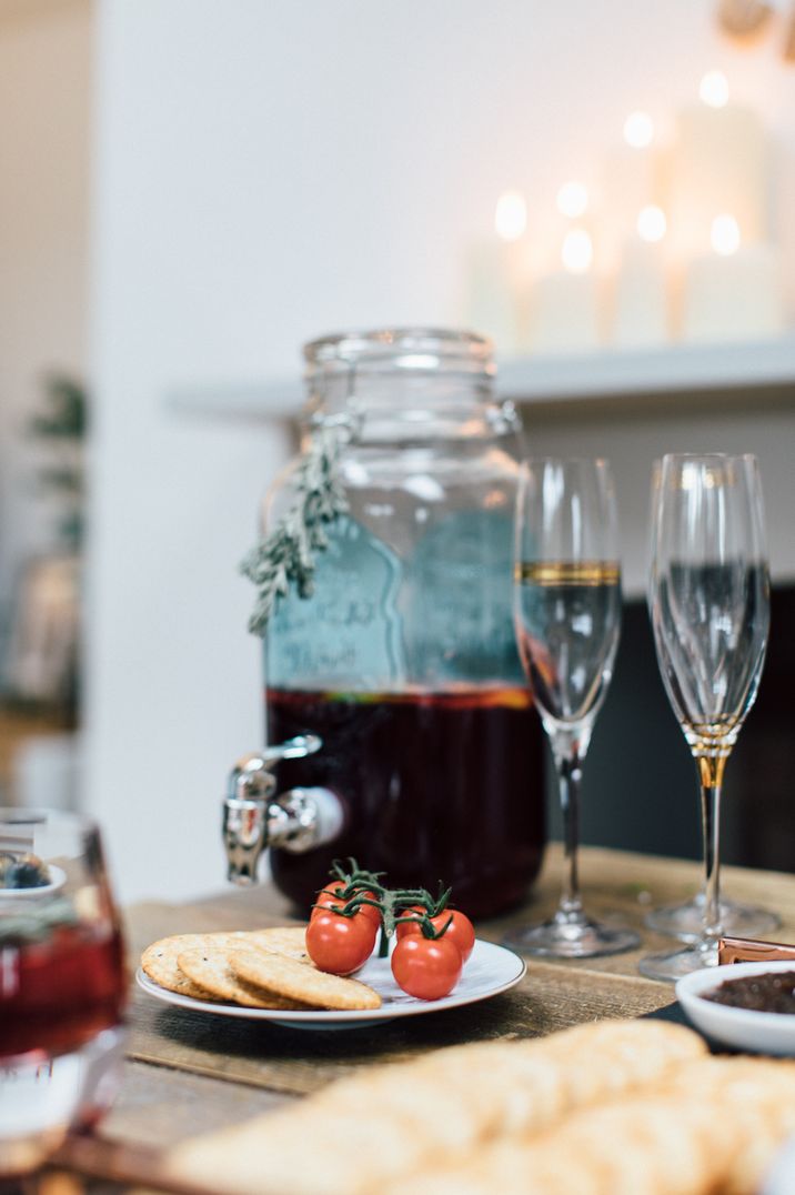 Mulled wine decanter, champagne glasses, vine tomatoes and crackers at Christmas soiree