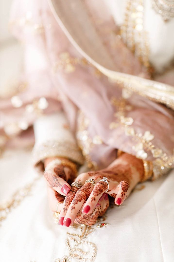 Bride with square shaped dark pink nails with henna and gold jewellery 