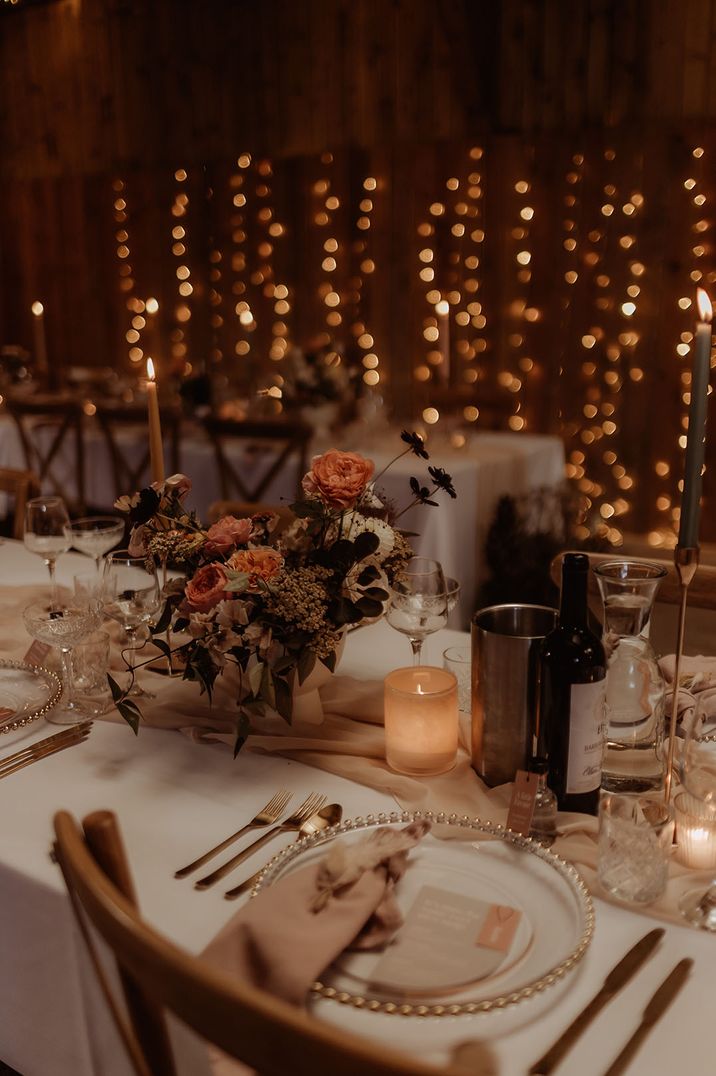 Fairy lights decorating barn wedding venue with soft pink blush theme and gold details 