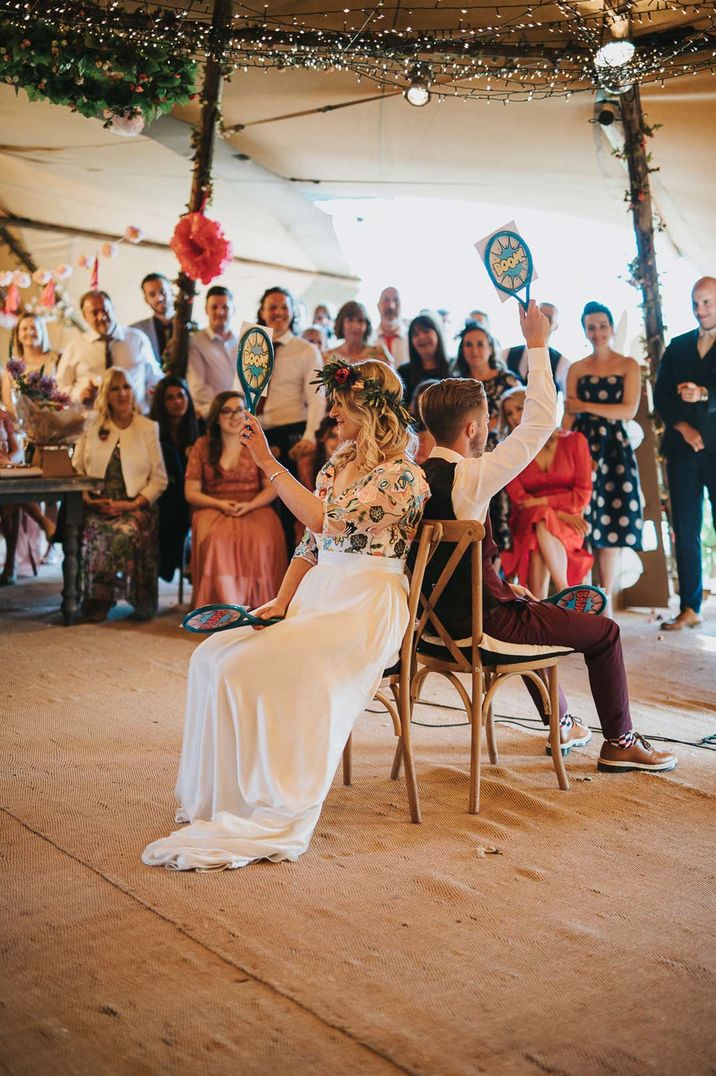 Bride and groom playing mr and mrs at the wedding with funny tennis rackets 