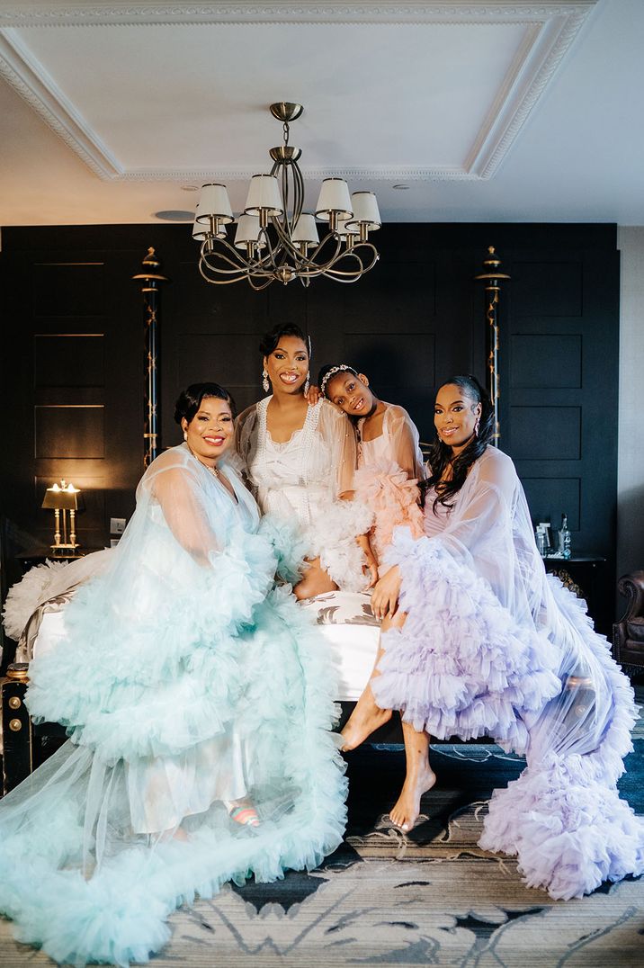 Bride and bridesmaids in pastel blue, pink, purple and white feather robes 