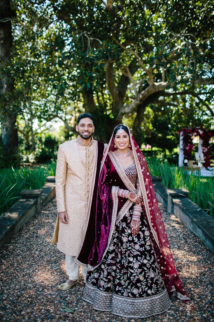 Multicultural Sri-Lankan and indian wedding with bride and groom in red and gold traditional outfits 