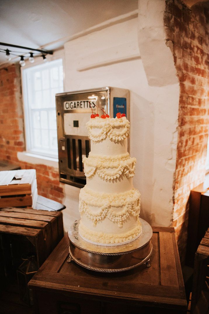 Large white three tier retro wedding cake topped with cherries for industrial wedding 