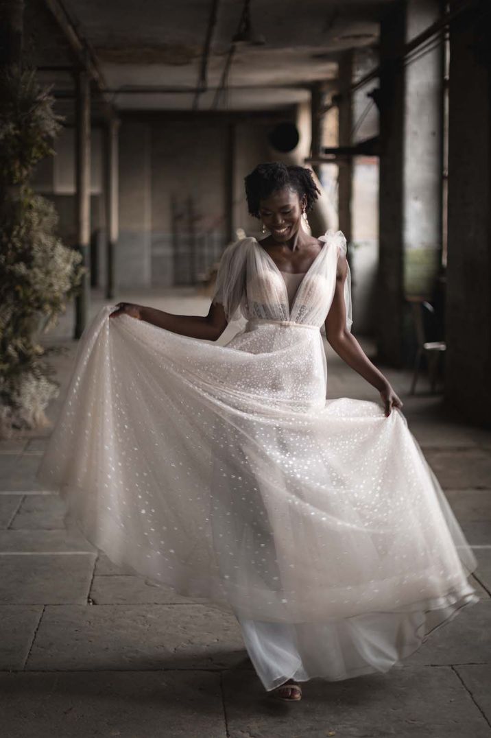 Bride wears sparkly wedding dress with sheer fabric and small tie to the waist 