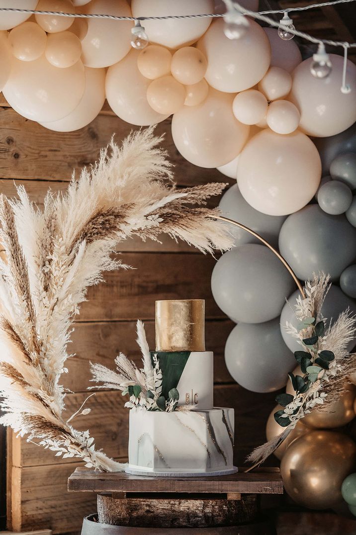 Three tier white, green and gold wedding cakes with boho pampas grass mini moongate and colourful balloons 