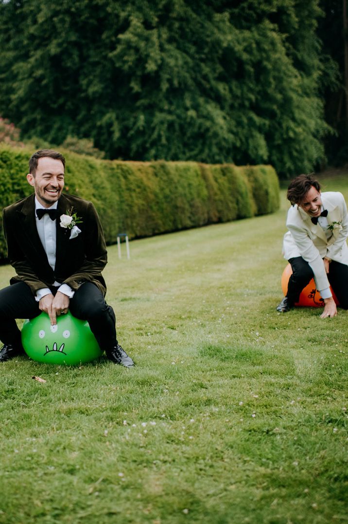 Groom and groomsman playing on space hoppers for outdoor entertainment idea 