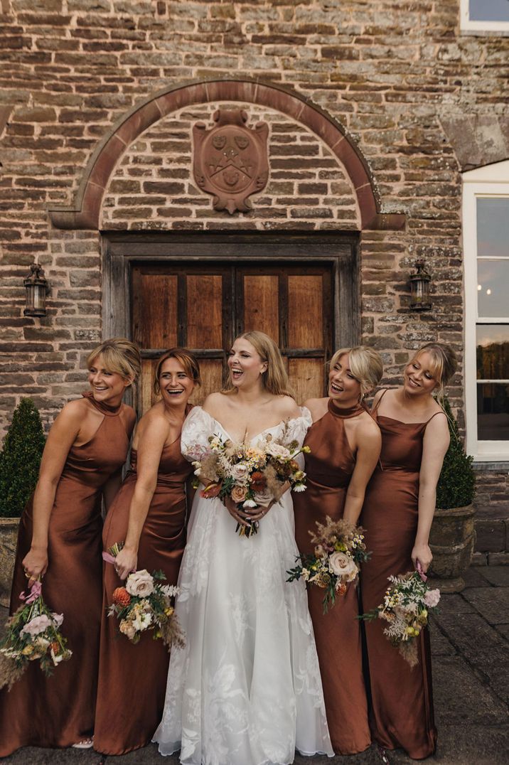 Bridal party wearing chocolate brown satin bridesmaid dresses with the bride at Dewsall Court 