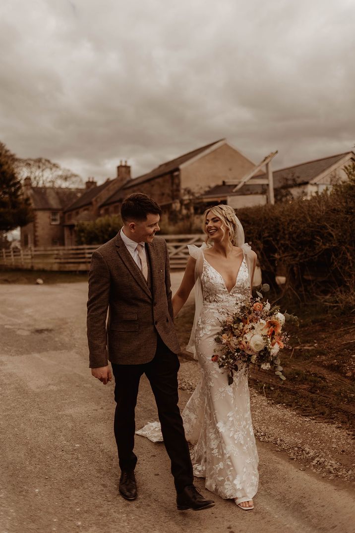 Bride in Made With Love wedding dress and groom in brown suit for barn wedding 