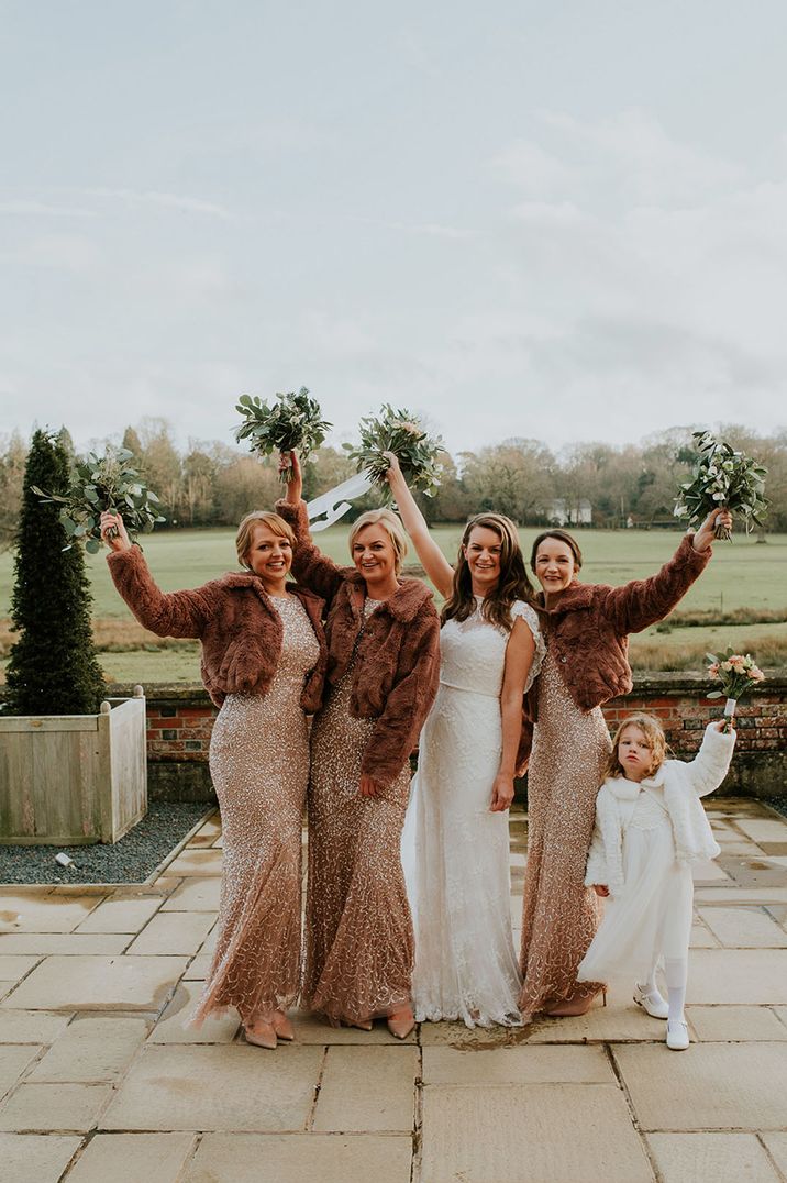 Bridal party with bridesmaids in sequin dresses and brown fur coat with flower girl in white 