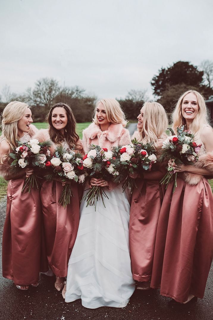 Bridesmaids in pink dresses with the bride in a pink faux fur personalised cover up 