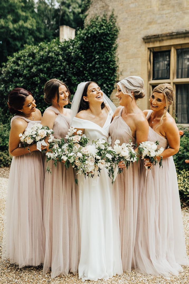 Bridesmaids in one shoulder pink bridesmaid dresses with the bride in chic off the shoulder wedding dress 