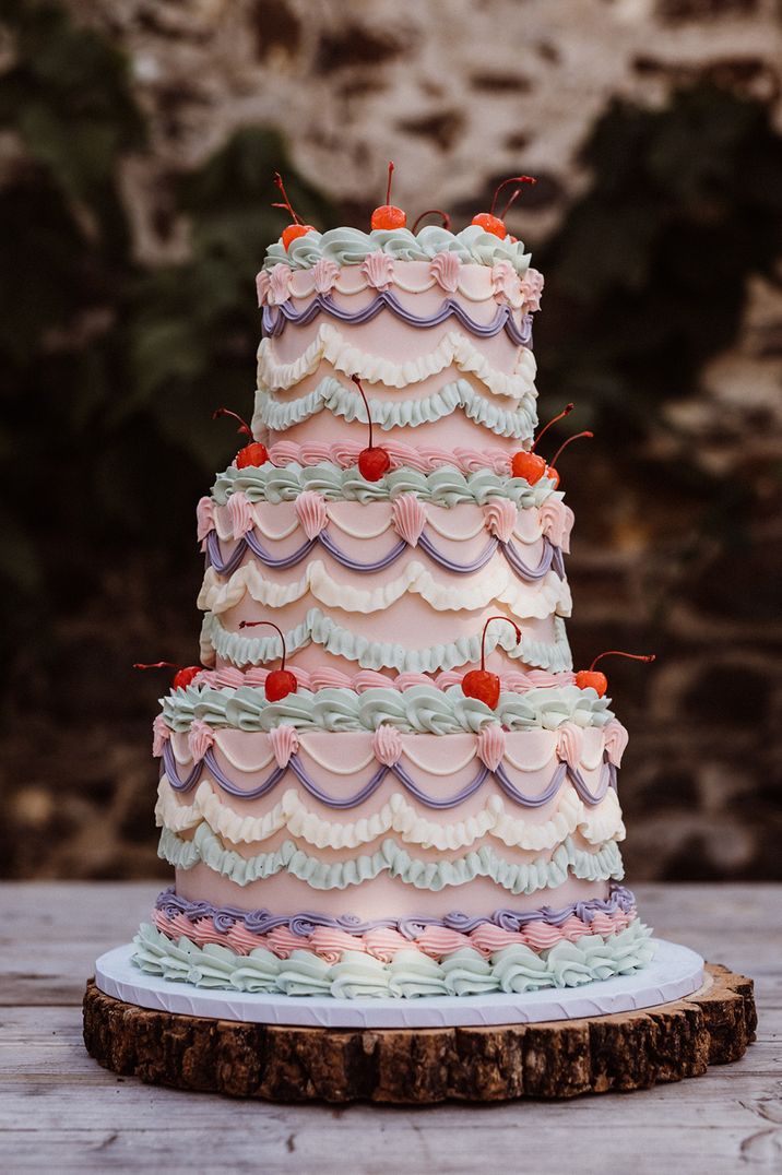 pastel pink retro wedding cake with ornate icing design and cherries 