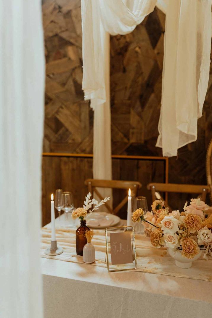 Muted wedding colour palette wedding tablescape with rose and carnation centrepieces, minimalistic decor and off-white wedding drapes at The Canary Shed wedding venue 