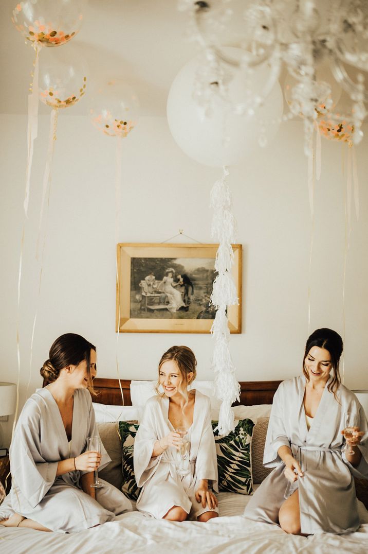 Bride and bridesmaids drinking champagne together as they get ready for the wedding 