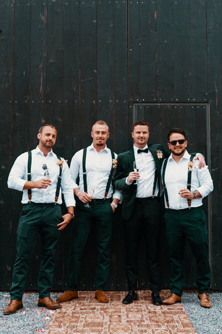 Groom and groomsmen in dark suits and sunglasses with dark green tuxes