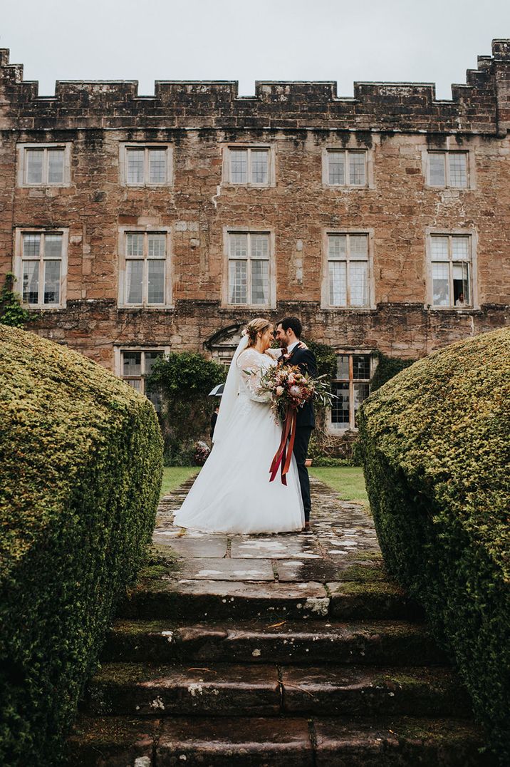 Askham Hall country house wedding venue with the bride and groom posing outside 