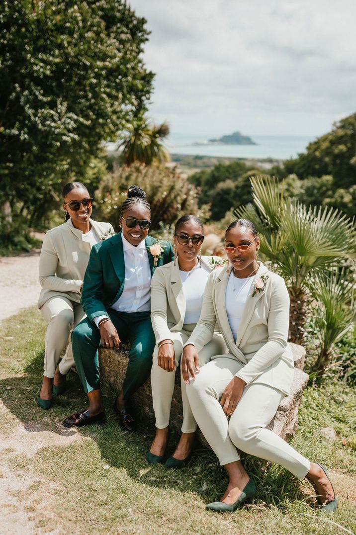 Bridal party in wedding suits. The Black bride wears a dark green suits and the bridal party light green bridesmaids suits