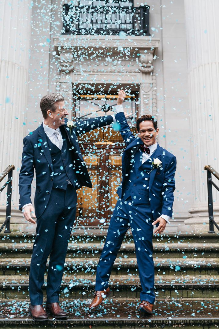 Grooms celebrate their marriage in blue suits to blue confetti 