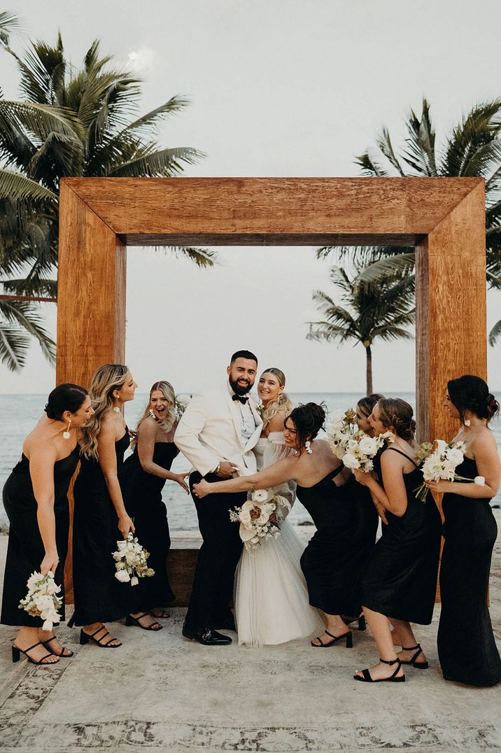 Beach wedding with the bridal party in black satin bridesmaid dresses