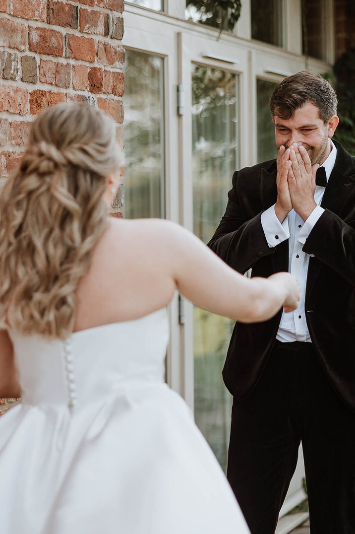 Groom in tuxedo cries as he sees the bride in a classic princess wedding dress at their country house wedding venue 