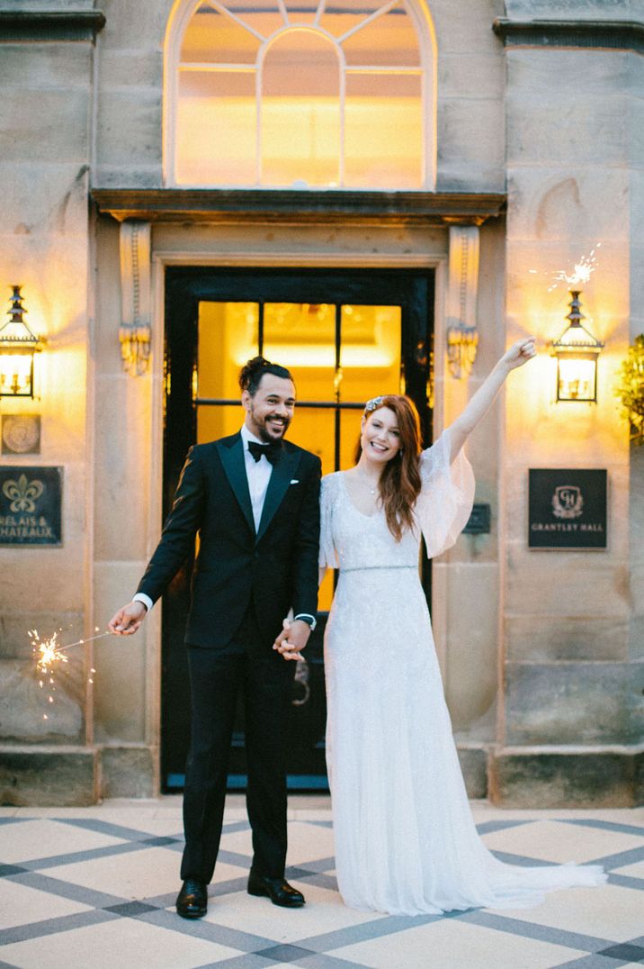 The bride in an embellished lace wedding dress with groom in black tuxedo on their wedding day 