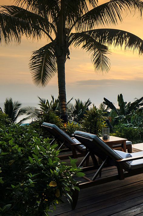 Image of honeymoon destination at Nihiwatu beach with deck chairs, palm trees and sunset 