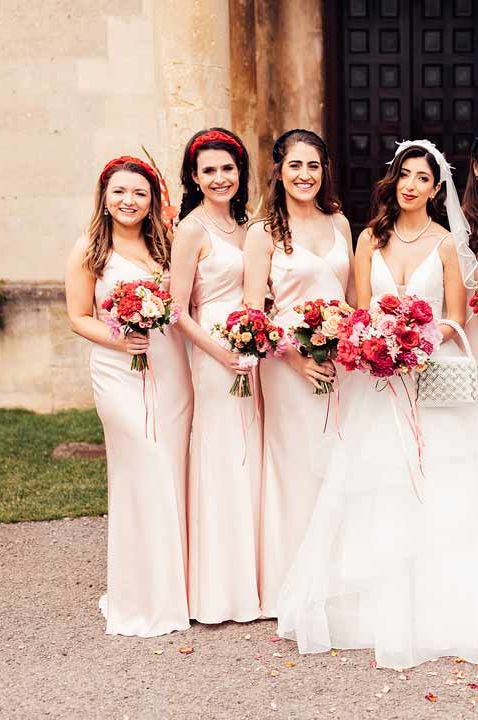 Mixed gender wedding party, bridesmaids wearing light pink satin bridesmaid dresses and bridesmate wearing dark navy suit