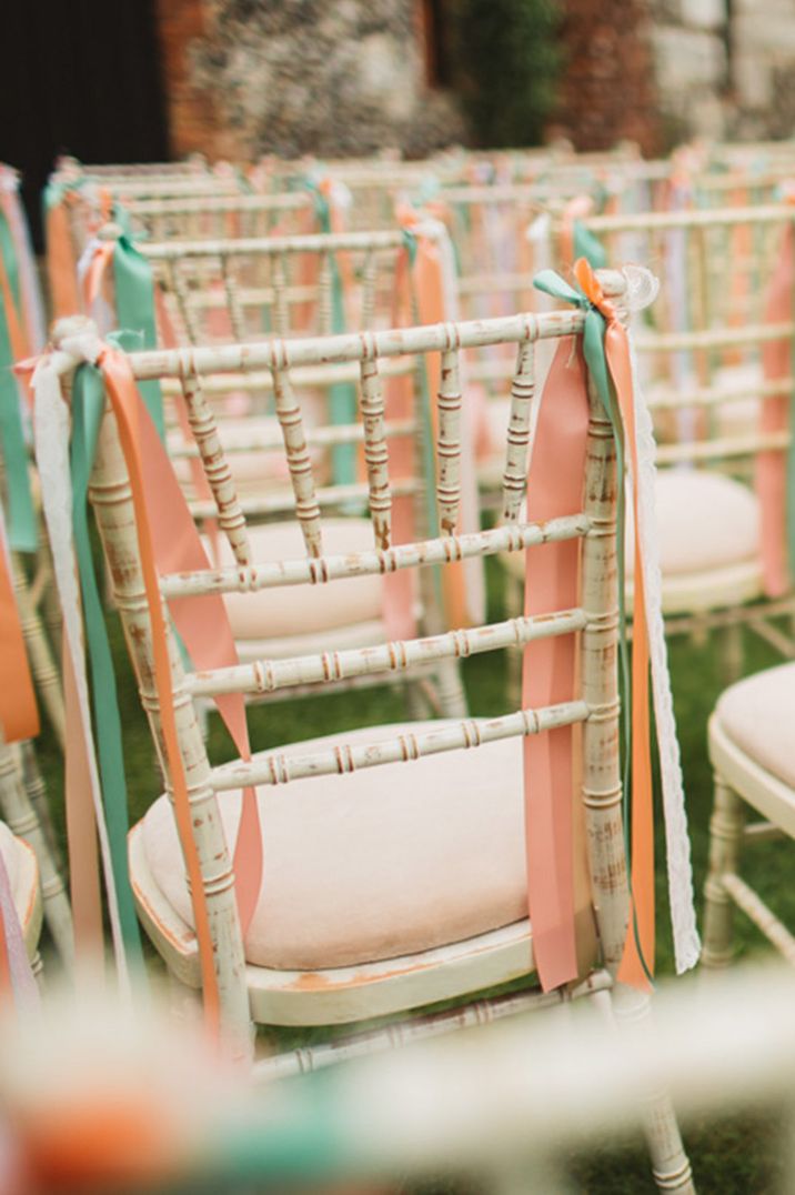 Pink, orange, green, and white ribbons tied onto the wedding chairs for the ceremony 