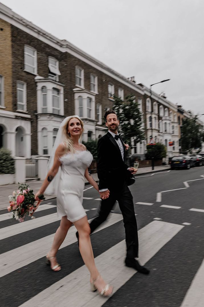 Short feather wedding reception dress with block heels worn by bride walking along the street with the groom 