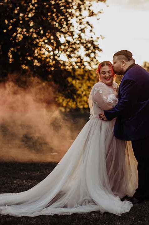 Bride in long sleeve sheer overlay wedding dress and groom in classic tuxedo - how far in advance should I get my wedding dress 